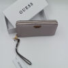Πορτοφόλι Guess γυναικείο σε blush pink χρώμα με wrist strap, μεταλλικές λεπτομέρειες και λευκό branded κουτί στο background.