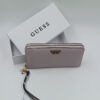 Πορτοφόλι Guess γυναικείο σε blush pink χρώμα με wrist strap, μεταλλικές λεπτομέρειες και λευκό branded κουτί στο background.