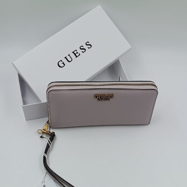 Πορτοφόλι Guess γυναικείο σε blush pink χρώμα με wrist strap, μεταλλικές λεπτομέρειες και λευκό branded κουτί στο background.