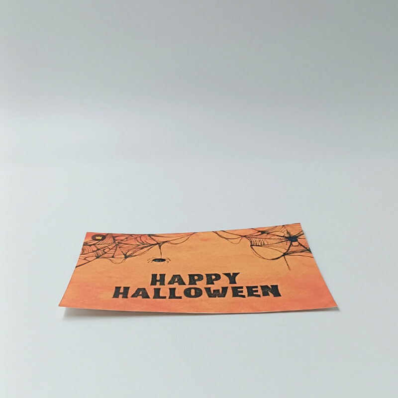 Ευχετήρια κάρτα πορτοκαλί Halloween με ιστούς αράχνης και μαύρο κείμενο “Happy Halloween”