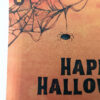 Ευχετήρια κάρτα πορτοκαλί Halloween με ιστούς αράχνης και μαύρο κείμενο “Happy Halloween”