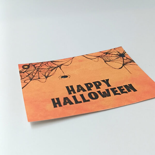 Ευχετήρια κάρτα πορτοκαλί Halloween με ιστούς αράχνης και μαύρο κείμενο “Happy Halloween”