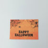 Ευχετήρια κάρτα πορτοκαλί Halloween με ιστούς αράχνης και μαύρο κείμενο “Happy Halloween”